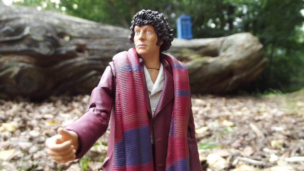 A Tom Baker action figure gesturing emphatically with the TARDIS on a log in the distance