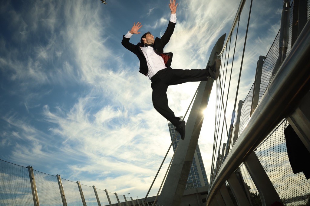 Kevin Burnard, in a tux, on a bridge, leaping into the air