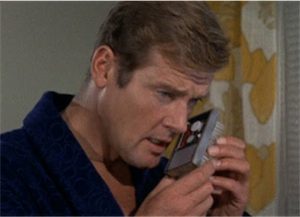 Roger Moore holding an electronic device to his ear