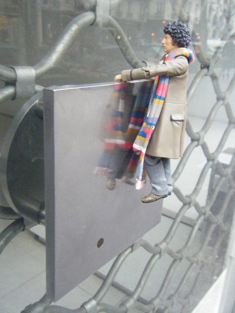 A Tom Baker action figure in his Season 17 outfit hanging from the doorhandle of the Galerie Denise René in Paris