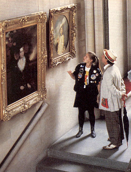 The Doctor and Ace looking up at a portrait of Ace in an eighteenth-century dress and feathered hat