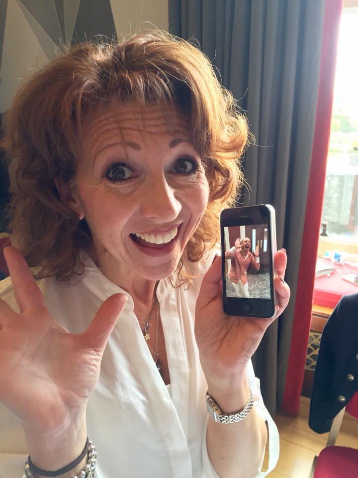 A bemused Bonnie Langford holding up a phone with a photo of Brendan dressed as Bonnie Langford in Time and the Rani
