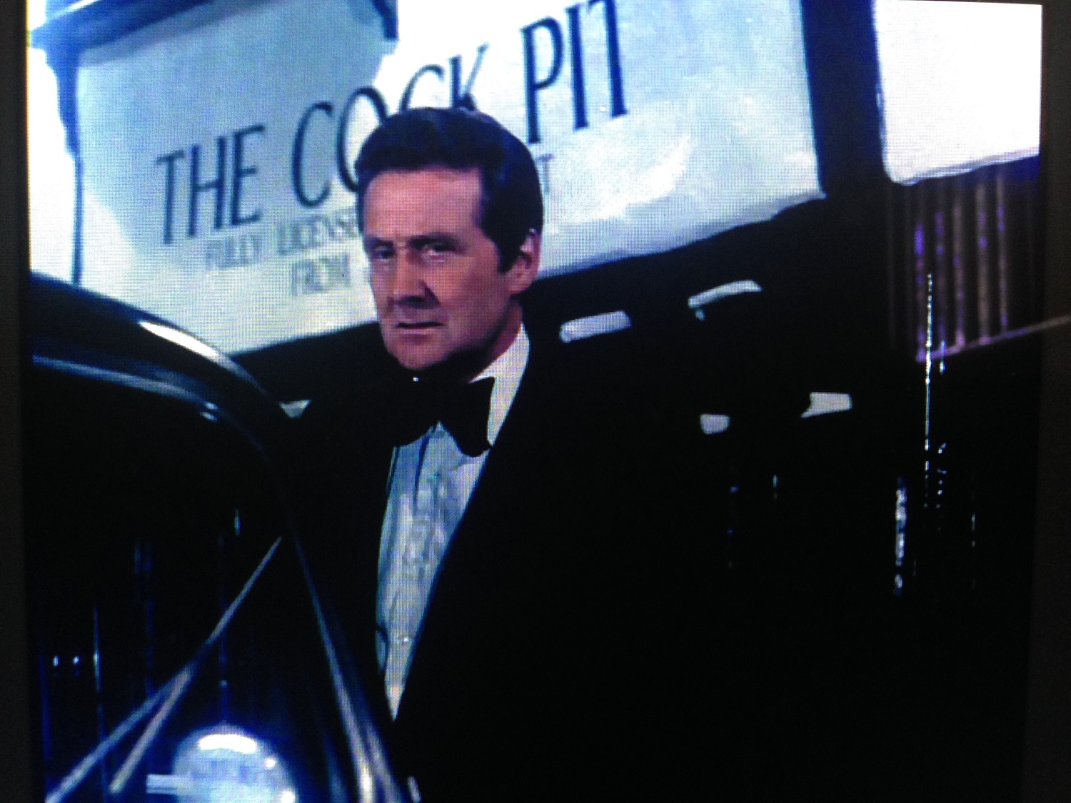 Patrick Macnee as Steed leaving a nightclub called The Cock Pit