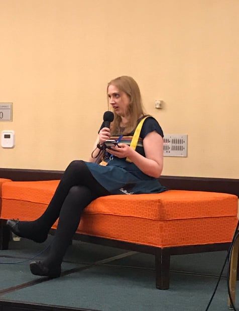 Lizbeth Myles sitting on an ottoman speaking into a microphone