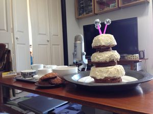 A multilayer cake shaped like a Chumbley on a table next to a microphone