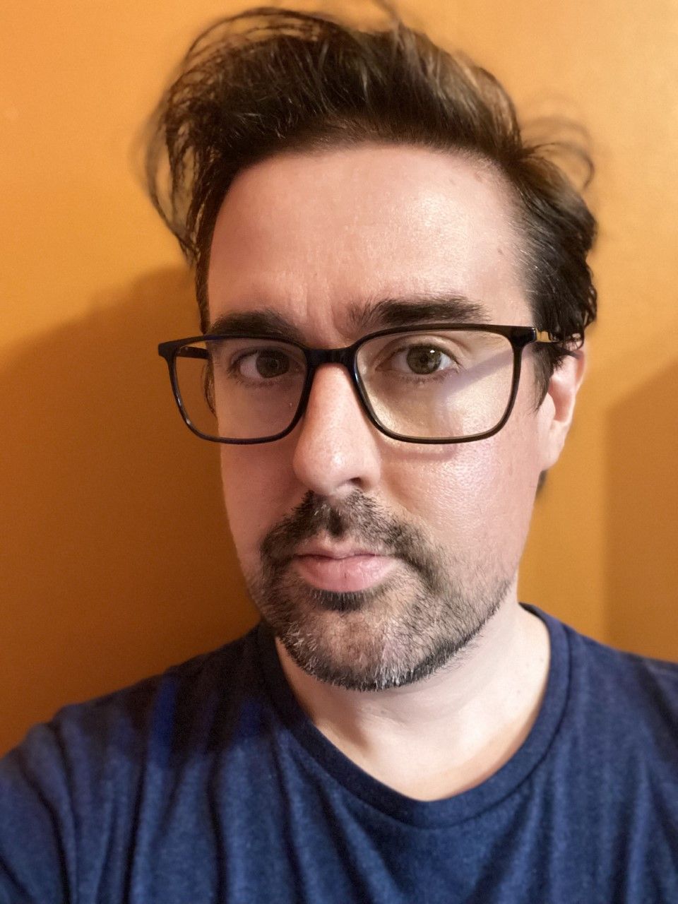 A headshot of Robert, a dark-haired unshaven man wearing glasses